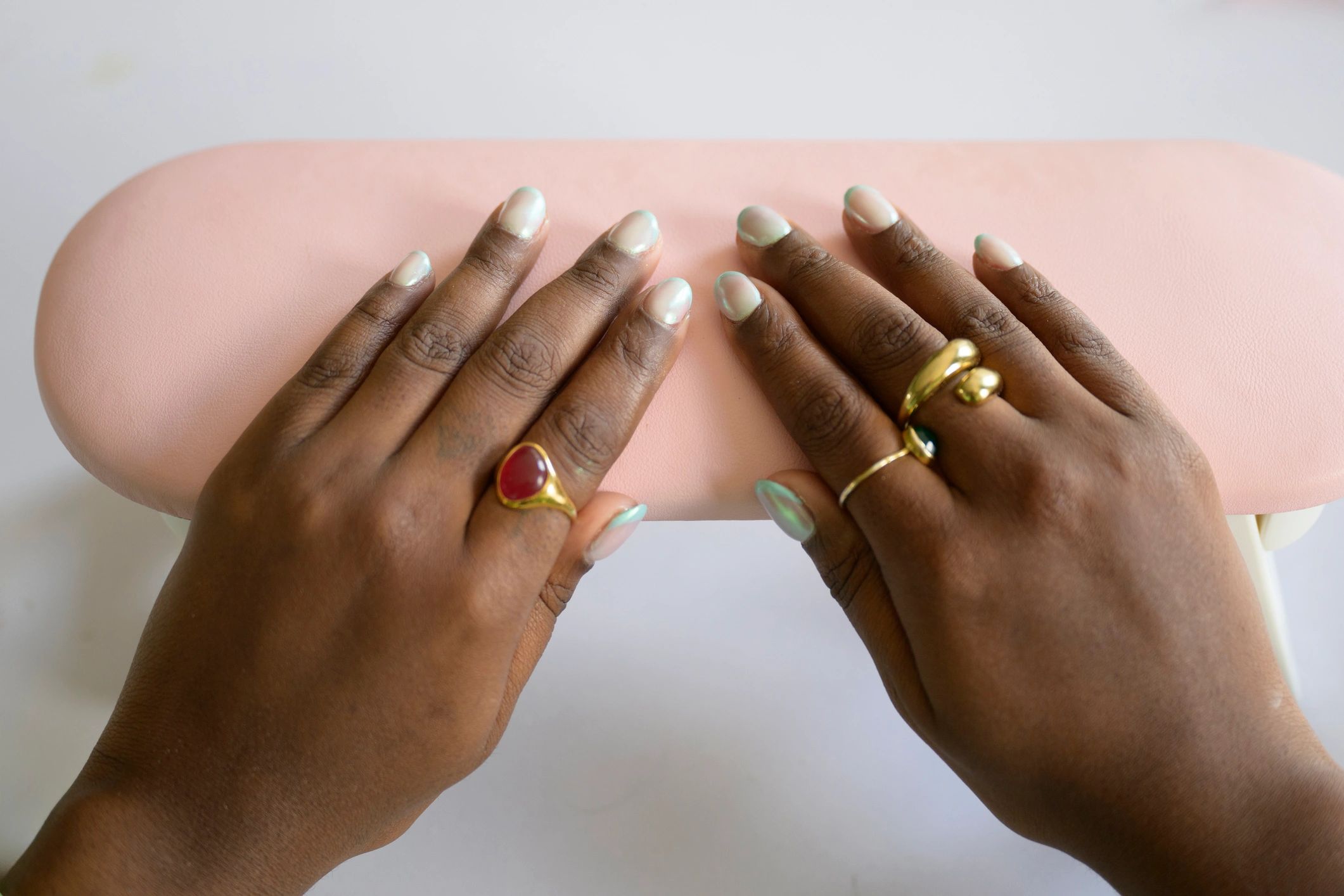 Freshly manicured hands of Black women with modern chrome French-tip nail art